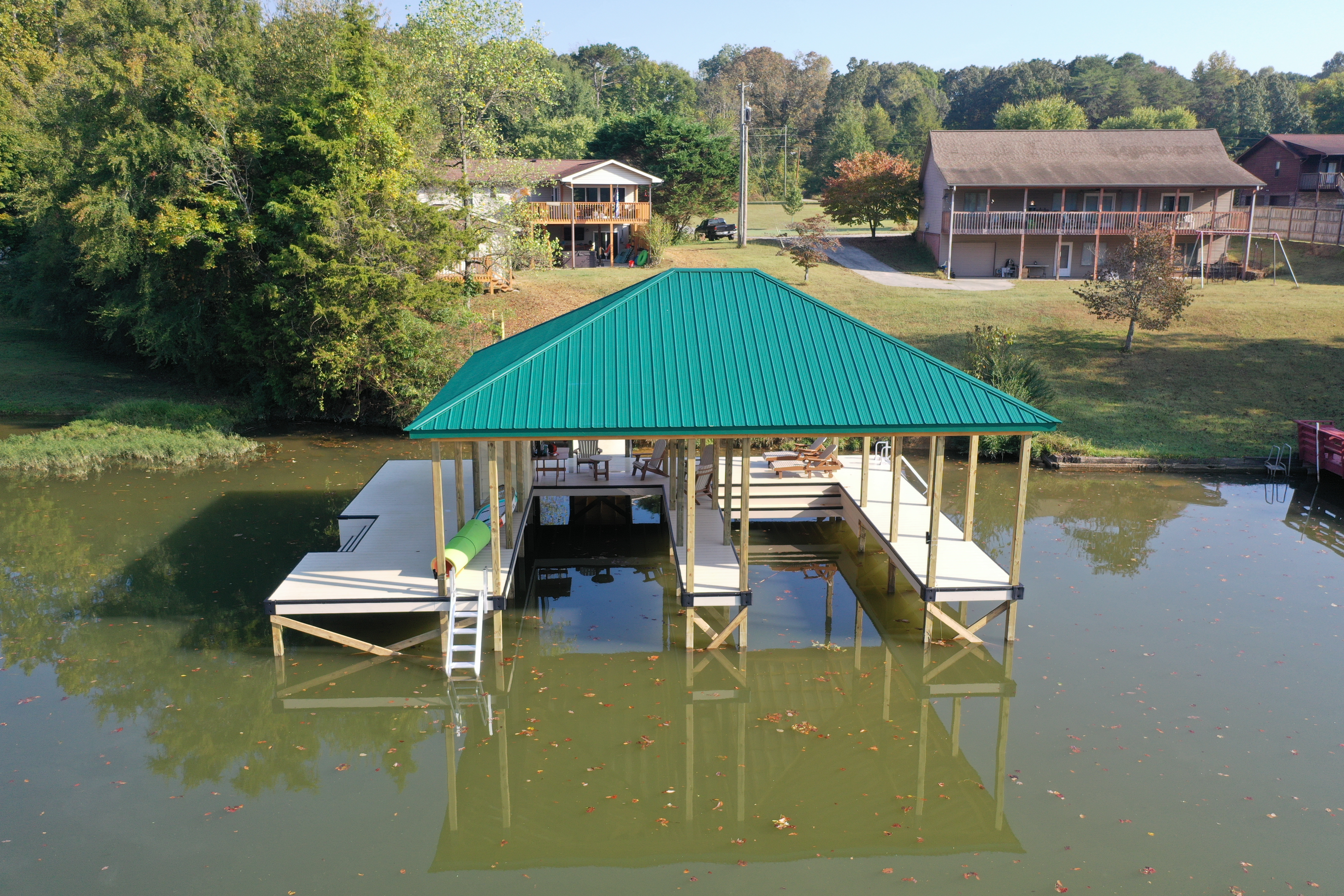Multi-slip fixed boathouse with green standing-seam metal roof on a Tennessee lake