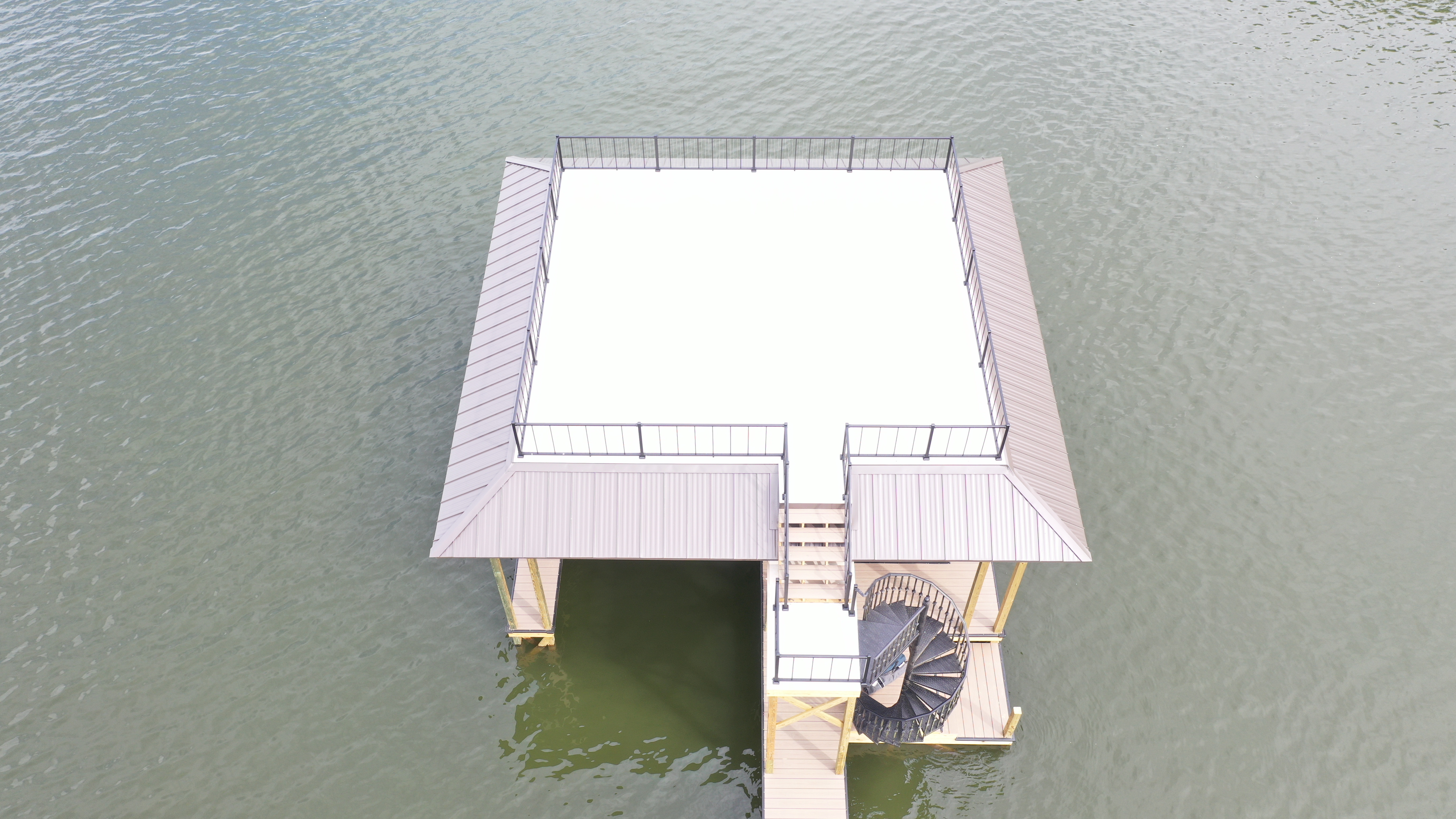 Aerial view of a two-story dock with a rooftop party deck and railing