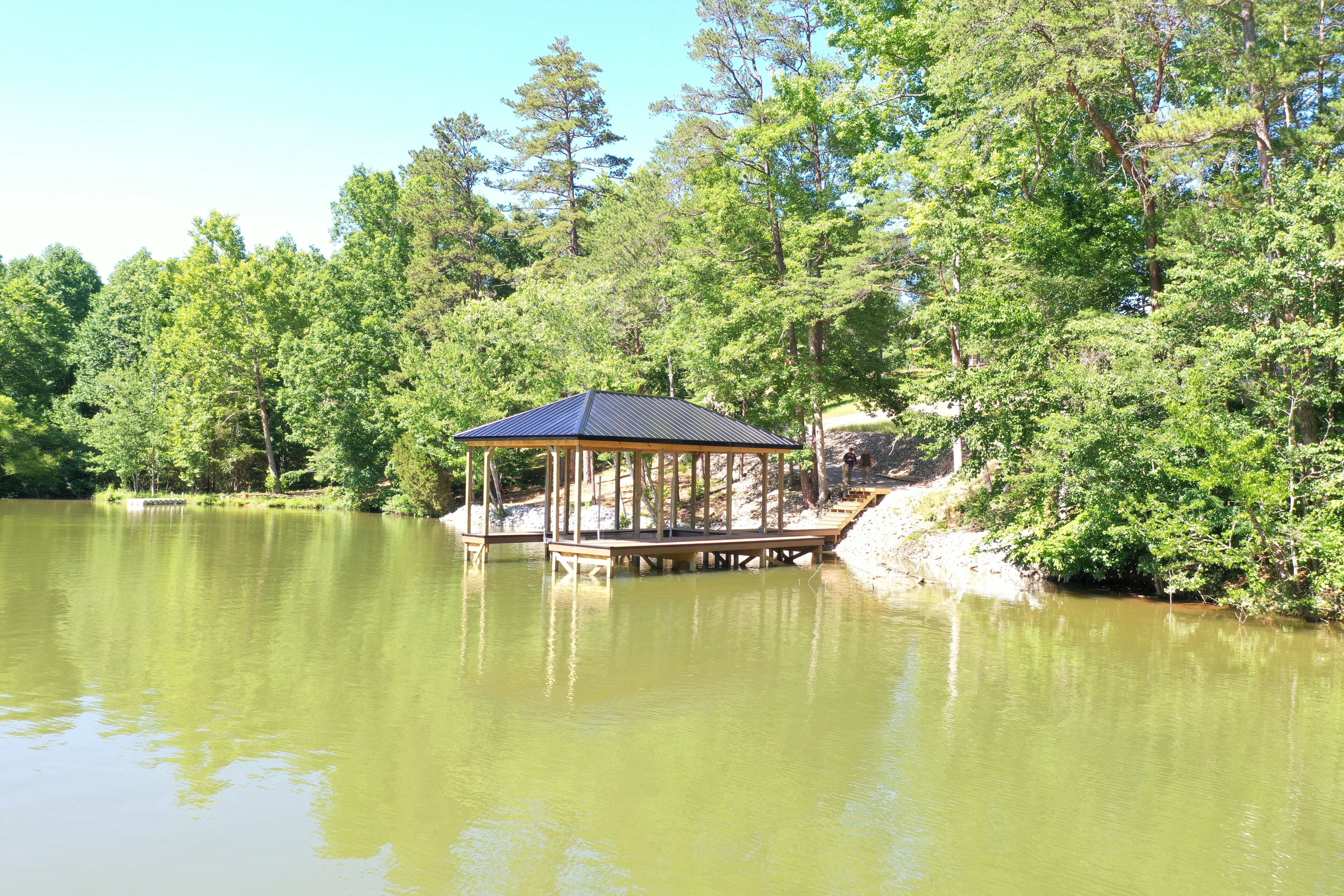 Detail of a wood-frame fixed dock pavilion with bench seating and metal roof