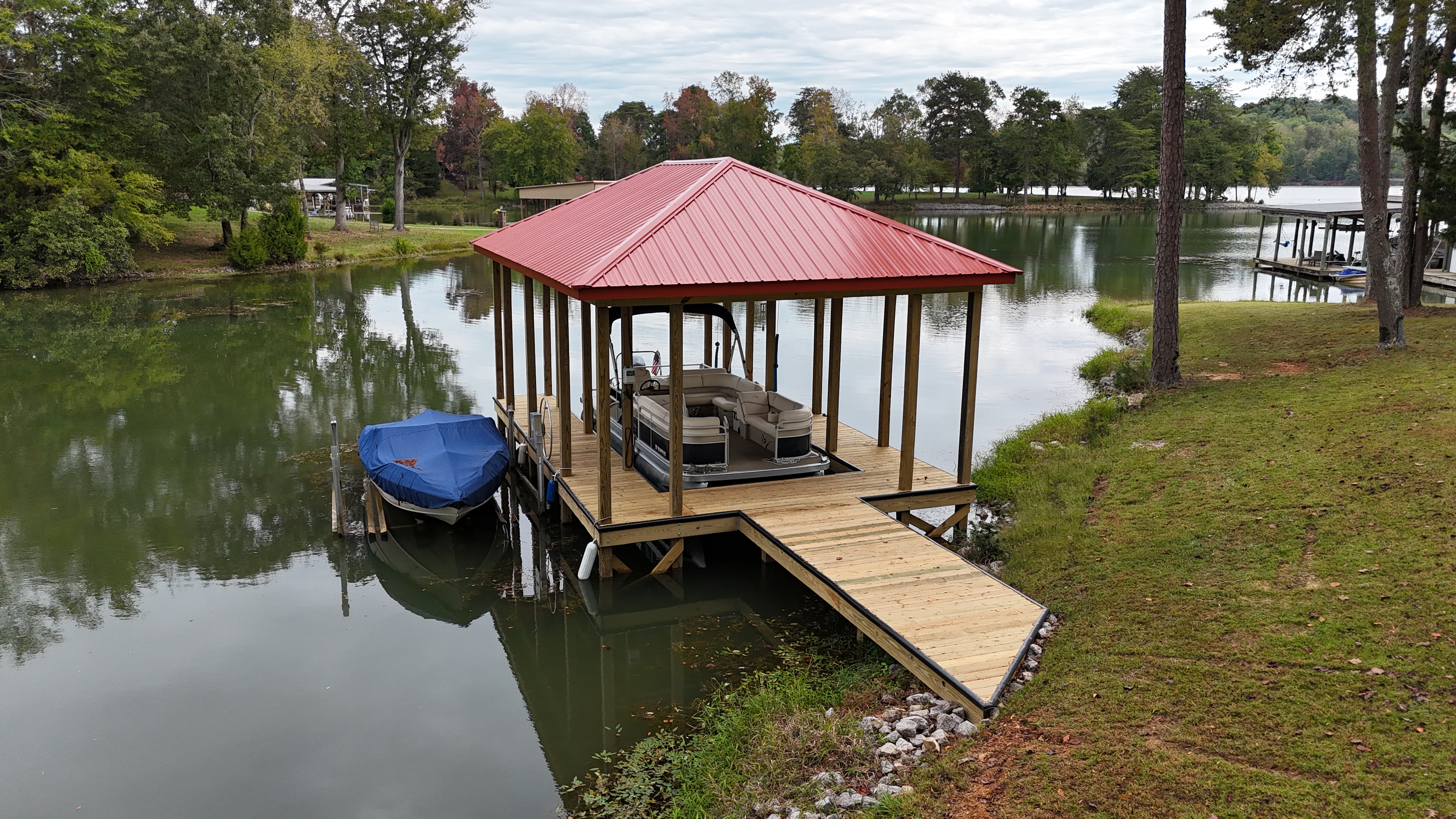 Red metal-roof open boathouse with pontoon slip on a Tennessee lake