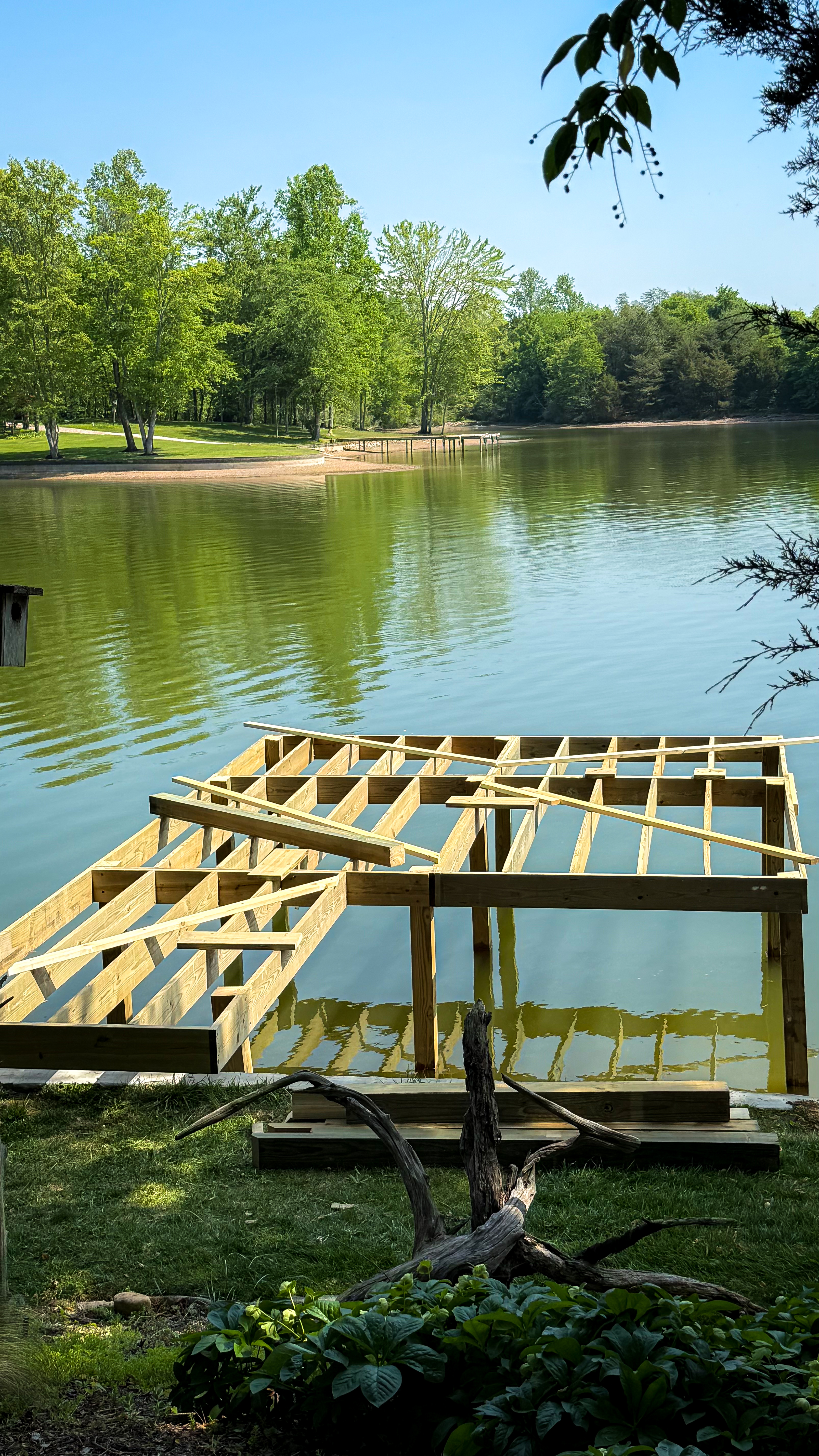 New dock frame on a calm Tennessee lake, surrounded by spring greenery